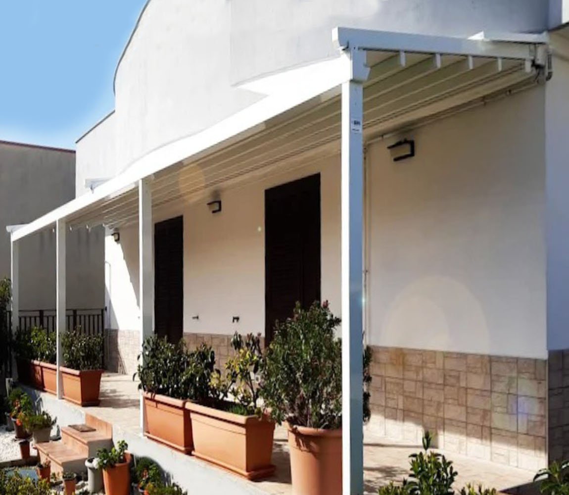 Pergotenda addossata in alluminio bianco installata sul terrazzo di un'abitazione